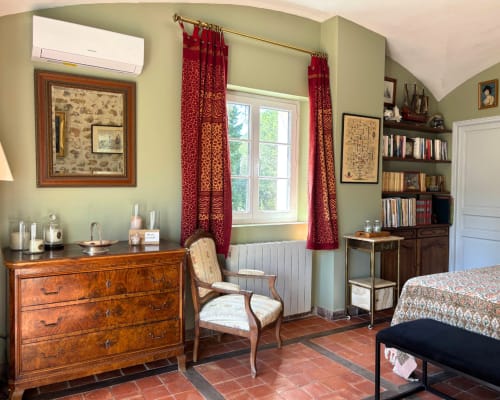 Adrien's room at Domaine Du Commandeur in Mondragon features elegant furnishings, red curtains, bookshelves, and garden views