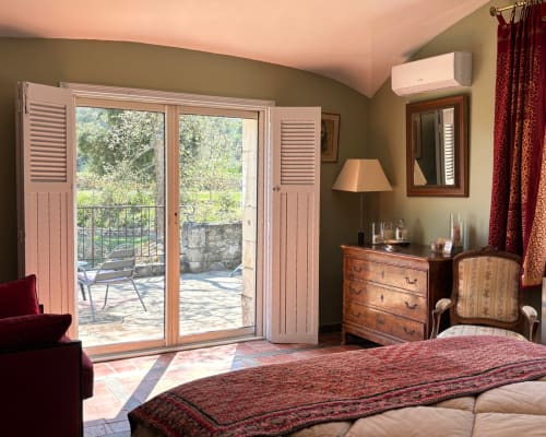 Adrien's room at Domaine Du Commandeur in Mondragon with garden view, featuring bed, wooden dresser, balcony doors, and air