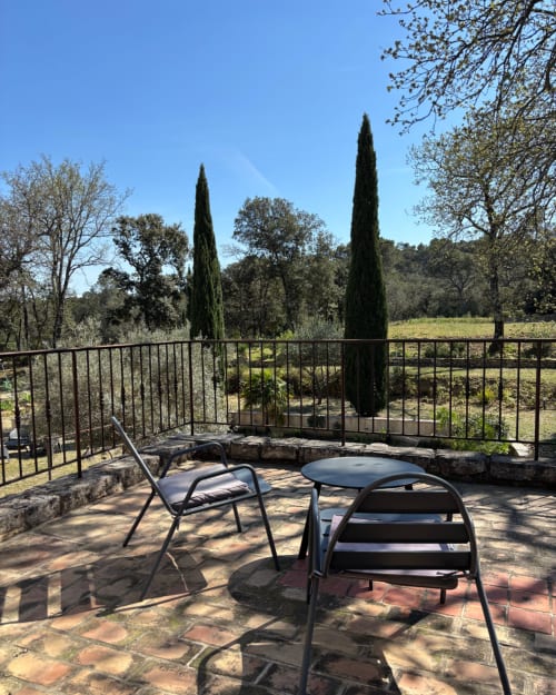Balcony view at Domaine Du Commandeur in Mondragon with patio chairs overlooking cypress trees and gardens