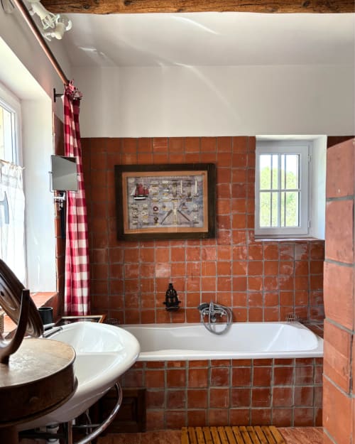 Rustic bathroom at Domaine Du Commandeur in Mondragon with terracotta tiles, white bathtub, and nautical decor