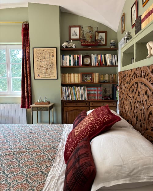 Adrien's room at Domaine Du Commandeur in Mondragon, featuring a bed with burgundy bedding, wooden carved headboard, and