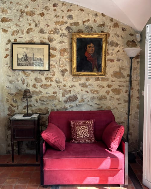 Adrien's room at Domaine Du Commandeur in Mondragon features a pink velvet chair against rustic stone walls with period