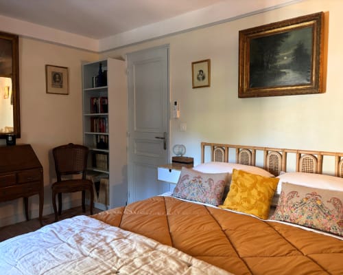 La chambre de Juana au Domaine Du Commandeur à Mondragon dispose d'un lit à tête de lit ornée, d'un bureau et de cadres sur fond crème