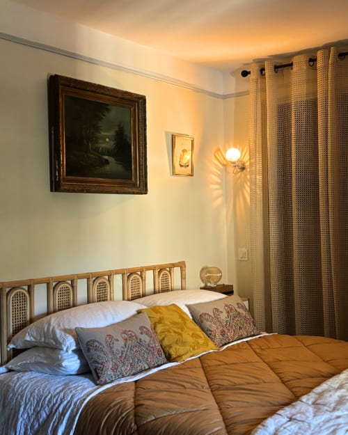 Cozy bedroom at Domaine Du Commandeur with framed artwork, patterned pillows, and warm lighting