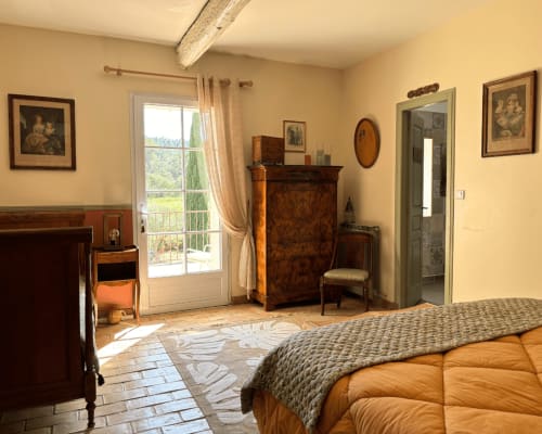 Isadora's room at Domaine Du Commandeur in Mondragon with period furniture, terracotta tile floor, and French doors opening