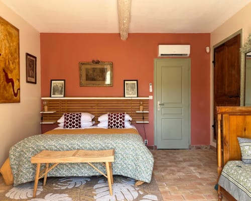 Isadora's room at Domaine Du Commandeur in Mondragon with terracotta walls, wooden bed frame, and period furnishings