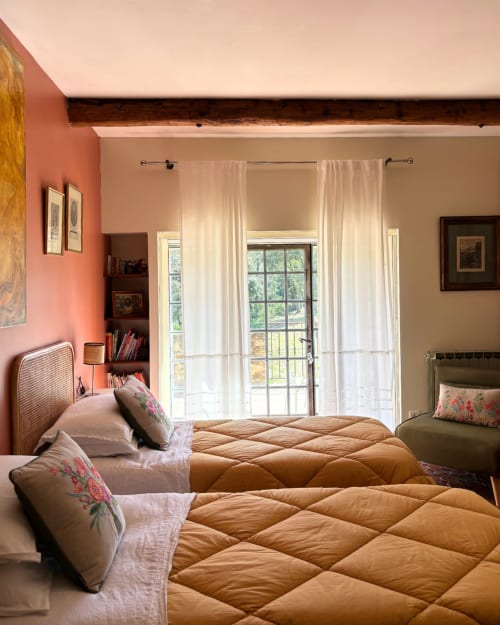 Chambre Alessandra at Domaine Du Commandeur, twin beds with tan quilts, coral accent wall, sheer curtains, balcony doors with