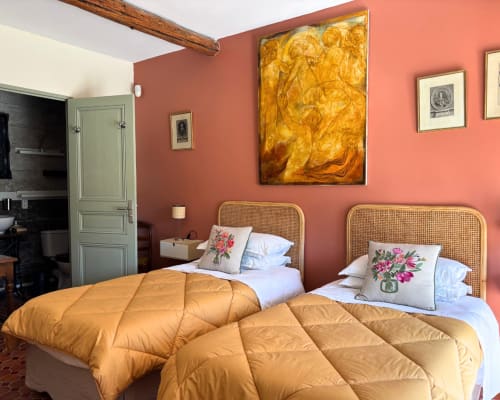 Chambre Alessandra at Domaine Du Commandeur in Mondragon with twin beds, rattan headboards, coral walls, and golden bedding
