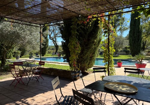 Patio couvert de pergola avec tables de restaurant surplombant une piscine bleue au Domaine Du Commandeur à Mondragon, France