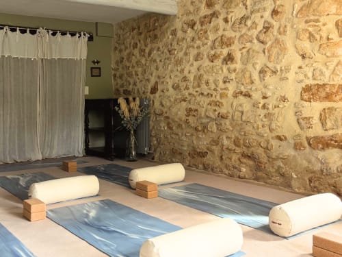 Studio de yoga au Domaine Du Commandeur avec tapis roulés, blocs en bois et murs en pierre à Mondragon