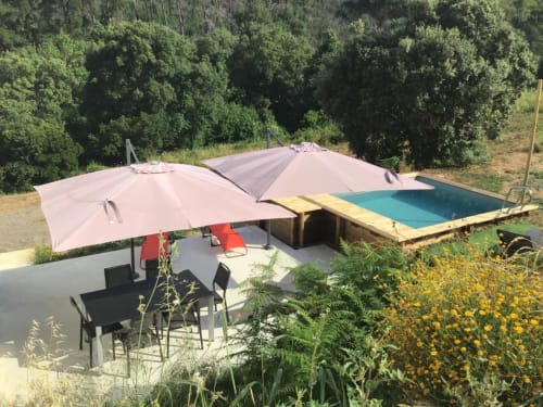 Corse et Zen pool area with pink umbrellas, lounge chairs, and wooden pool deck surrounded by forest in Taglio Isolaccio,