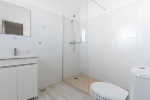 Banheiro moderno na Galagana Charm House com chuveiro de vidro, azulejos brancos e pia na Golegã