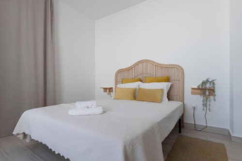 Quarto iluminado na Galagana Charm House B&B em Golegã com cabeceira de rattan, almofadas amarelas, roupa de cama branca e estilo minimalista