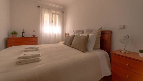 Quarto luminoso na Gomes Equestre Alojamento em Golegã com móveis de madeira, roupa de cama branca e luz natural