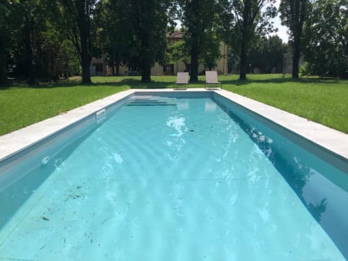 Piscina rettangolare all'Hotel Villa Dom a Piacenza con acqua turchese cristallina, lettini e ombrelloni.