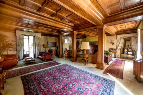 Lussuosa suite con travi in legno a Villa Dom di Piacenza, tappeti ricamati, sedute in pelle rossa e arredi eleganti