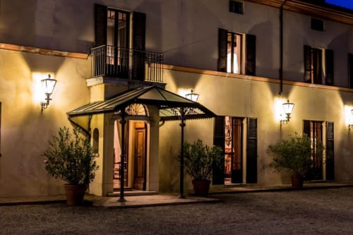 Ingresso dell'hotel Villa Dom a Piacenza con elegante corte illuminata, pergolato e piante in vaso di notte