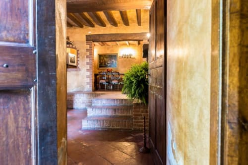Corridoio d'ingresso della Villa Dom hotel a Piacenza con gradini in mattoni, porte in legno e decorazioni classiche