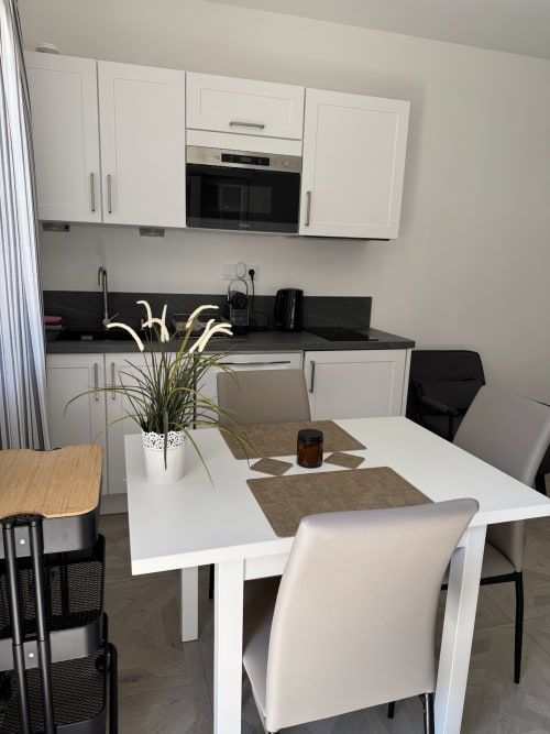 Cuisine-salle à manger moderne du Studio Montségur au Domaine de Bize avec mobilier blanc, plan de travail noir et table