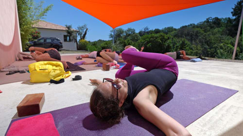 Outdoor yoga class on rooftop at Corse et Zen wellness hotel in Corsica under orange shade sail