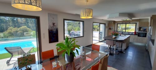Open-plan kitchen and dining area at Corse et Zen with pool view, modern furnishings, and natural lighting