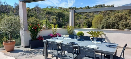 Elegant rooftop terrace at Corse et Zen with dining table, forest views, and blooming flowers in Taglio Isolaccio