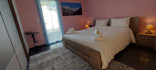 Modern bedroom at Corse et Zen hotel in Taglio Isolaccio with pink walls, white bedding, and balcony access