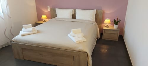 Corse et Zen hotel bedroom in Taglio Isolaccio with wooden bed, white linens, bedside lamps, and pink accent wall
