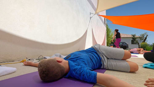 Guests practicing yoga on mats outdoors under shade sails at Corse et Zen wellness retreat in Corsica