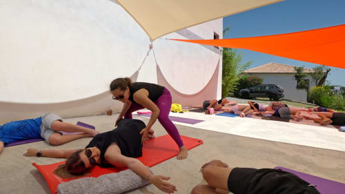 Instructor guides yoga class outdoors at Corse et Zen hotel in Corsica under colorful shade sails