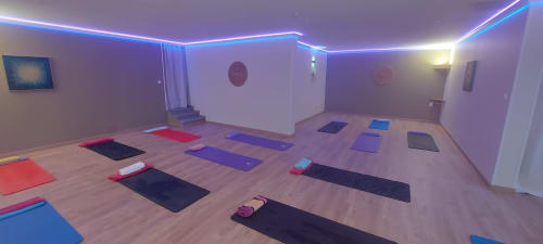 Modern yoga studio at Corse et Zen hotel with colorful mats, blue neon lighting, and wooden flooring in Taglio Isolaccio