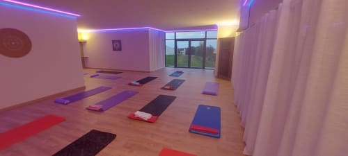 Modern yoga and meditation studio at Corse et Zen with purple neon accents, yoga mats, and panoramic windows overlooking