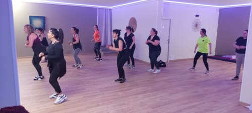 Group fitness class in purple-lit studio at Corse et Zen hotel with participants exercising on wooden floor