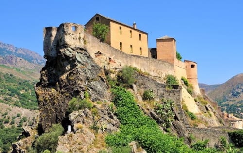 Historic fortress-castle perched on rocky cliff in Corsica, Taglio Isolaccio, surrounded by green mountains