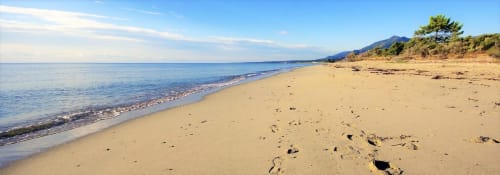Sandy beach in Corsica with clear blue waters and mountains, Corse et Zen hotel location