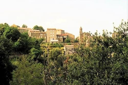 Corse et Zen hotel nestled among lush greenery in Taglio Isolaccio, Corsica with traditional stone buildings on hillside
