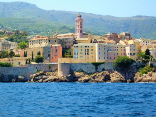 Coastal Italian village with colorful buildings and bell tower overlooking blue Mediterranean Sea