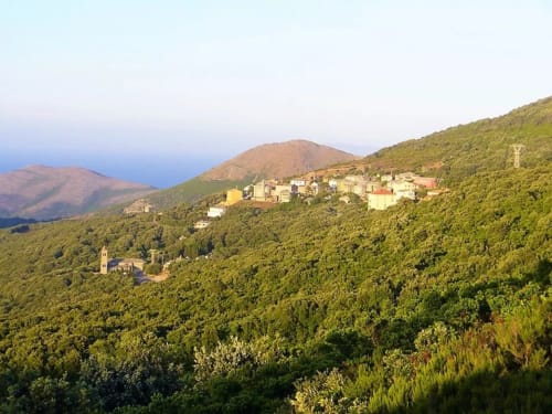 Corse et Zen hillside village nestled among green forests with mountains and blue sea beyond, Taglio Isolaccio
