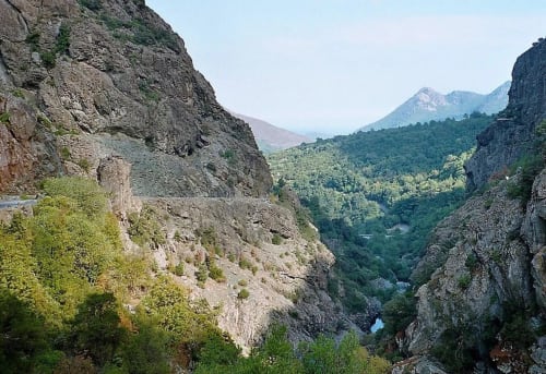 Gorge de montagne rocheuse avec végétation verdoyante et pics lointains près de Taglio Isolaccio, Corse