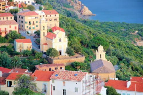 Hôtel Corse et Zen à Taglio Isolaccio, bâtiments aux toits rouges nichés dans les collines verdoyantes surplombant la côte méditerranéenne