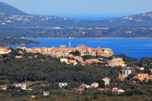 Village côtier niché sur une colline surplombant la mer Méditerranée bleu azur en Corse