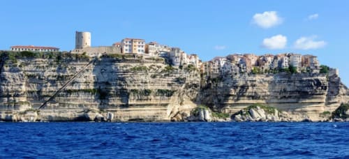 Village perché de Bonifacio en Corse : bâtisses historiques en pierre dominant les falaises blanches de calcaire et la mer bleue