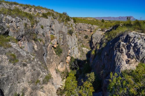Paisaje de cañón rocoso con vegetación verde y montañas cerca de Blanca, España