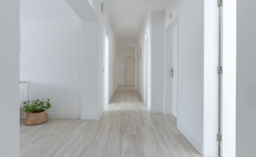 Corredor moderno da Galagana Charm House em Golegã com piso de madeira clara, paredes brancas e portas para os quartos de hóspedes