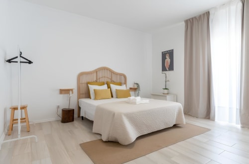 Quarto moderno na Galagana Charm House com cama de vime, almofadas amarelas e decoração minimalista em Golegã, Portugal