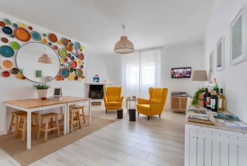 Ampla sala de estar aberta na Galagana Charm House em Golegã com cadeiras mostarda, arte de parede com pratos coloridos e madeira