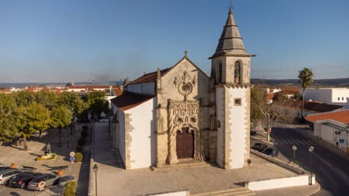 Igreja histórica em Golegã, Portugal com campanário e fachada de pedra com vista para a praça da cidade