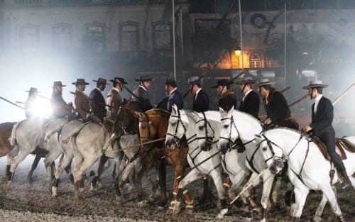 Cavaleiros em traje formal montando cavalos branco e marrom em Golegã, a famosa tradição de feira de cavalos de Portugal.