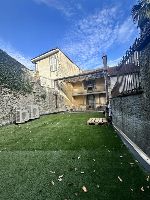 Innenhof mit Kunstrasen im Hotel Ombre de la Tour in Lourdes, Steingebäude umgeben eine Grünfläche