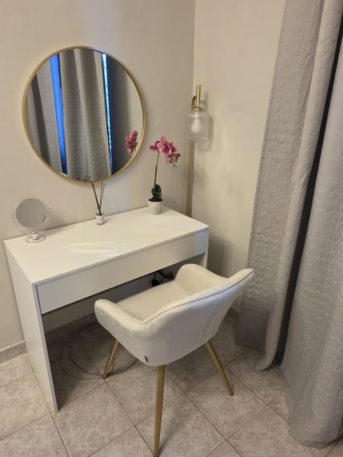 Elegante toeletta con specchio rotondo, sedia bianca e orchidea rosa nell'appartamento Manzoni 1 di THE V Collection, Turate